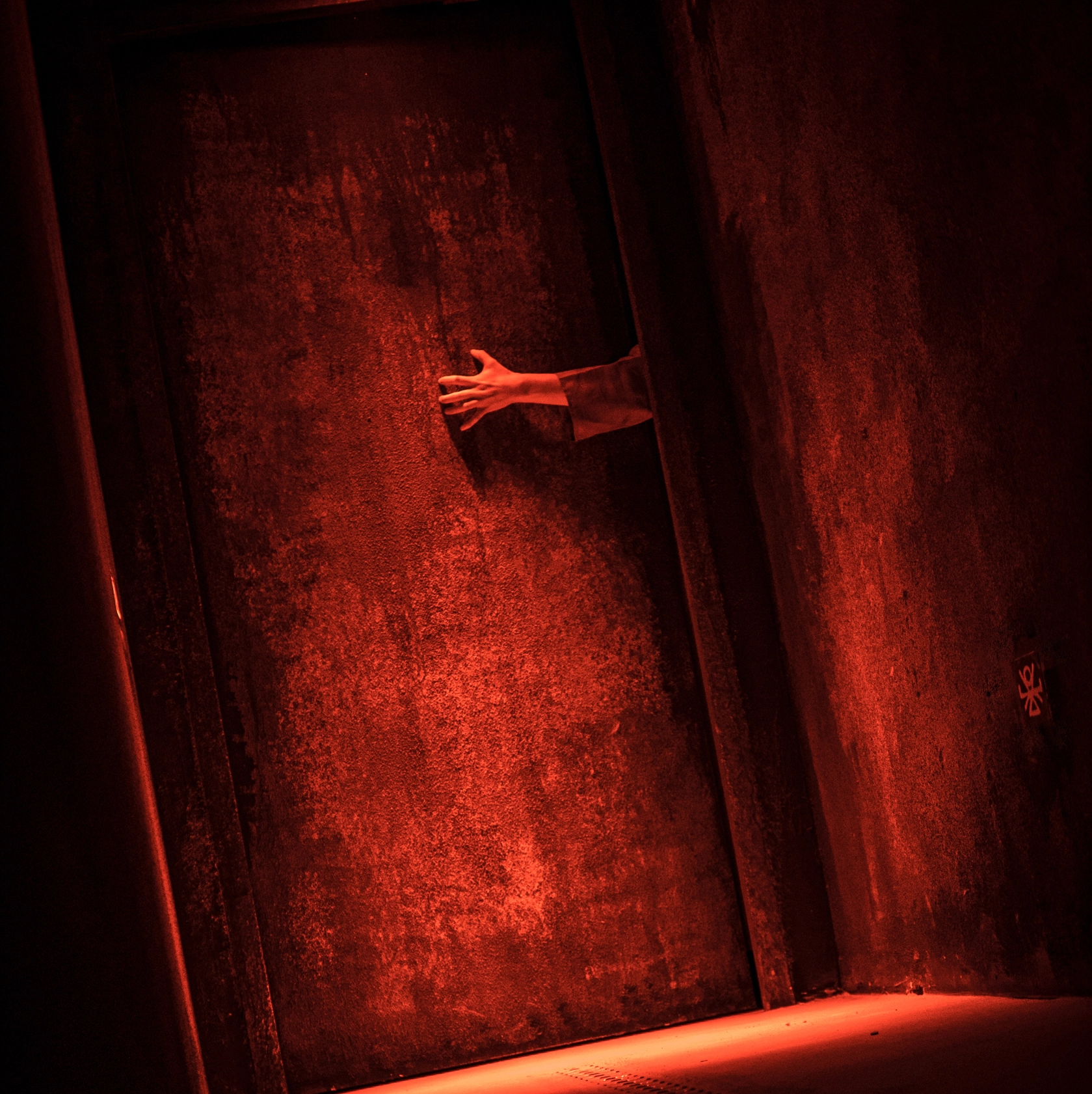 L'Antre Le Sacrifice, photo d'un mur rouge et d'une main, par Manon Brin
